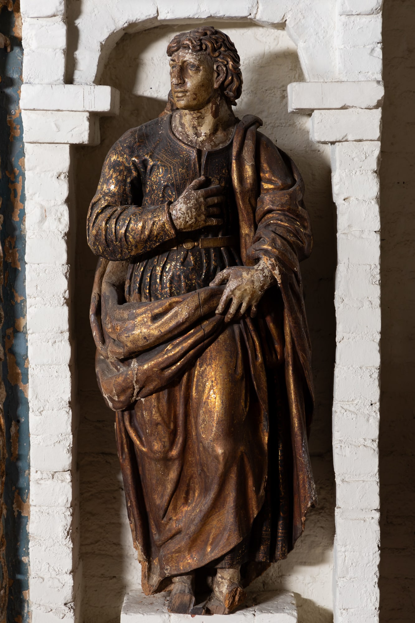 A Carved Wood Parcel-Gilt and Polychrome-Painted Figure of a Saint: depicted standing with right hand over heart, wearing a richly patterned robe 54 x 19 x 13 in. (137.2 x 48.3 x 33 cm.) Provenance: Property from the Estate of Francis and Marion Lederer Illustrated: "
