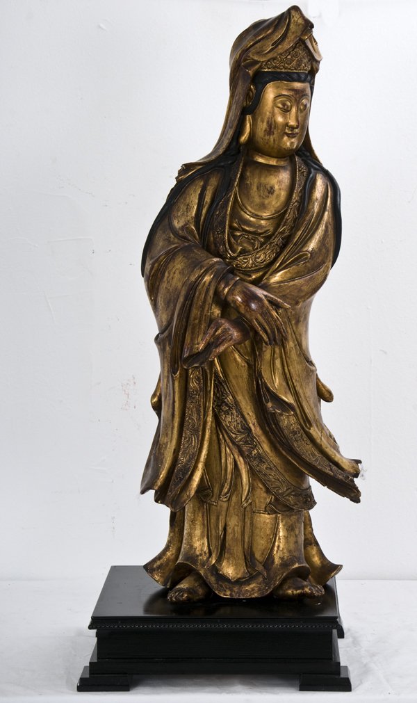CHINESE CARVED AND GILTWOOD QUAN YIN: with an ebonized wood base of a later date Condition: with loss and repair to fingers and feet 34 1/2 inches high
