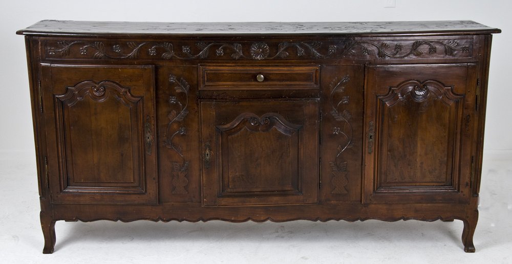 LOUIS XV PROVINCIAL WALNUT BUFFET: the rectangular top above a floral carved frieze, central drawer and cupboard flanked by a pair of cartouche paneled doors 78 1/2 inches wide; 17 inches deep; 39 inches high