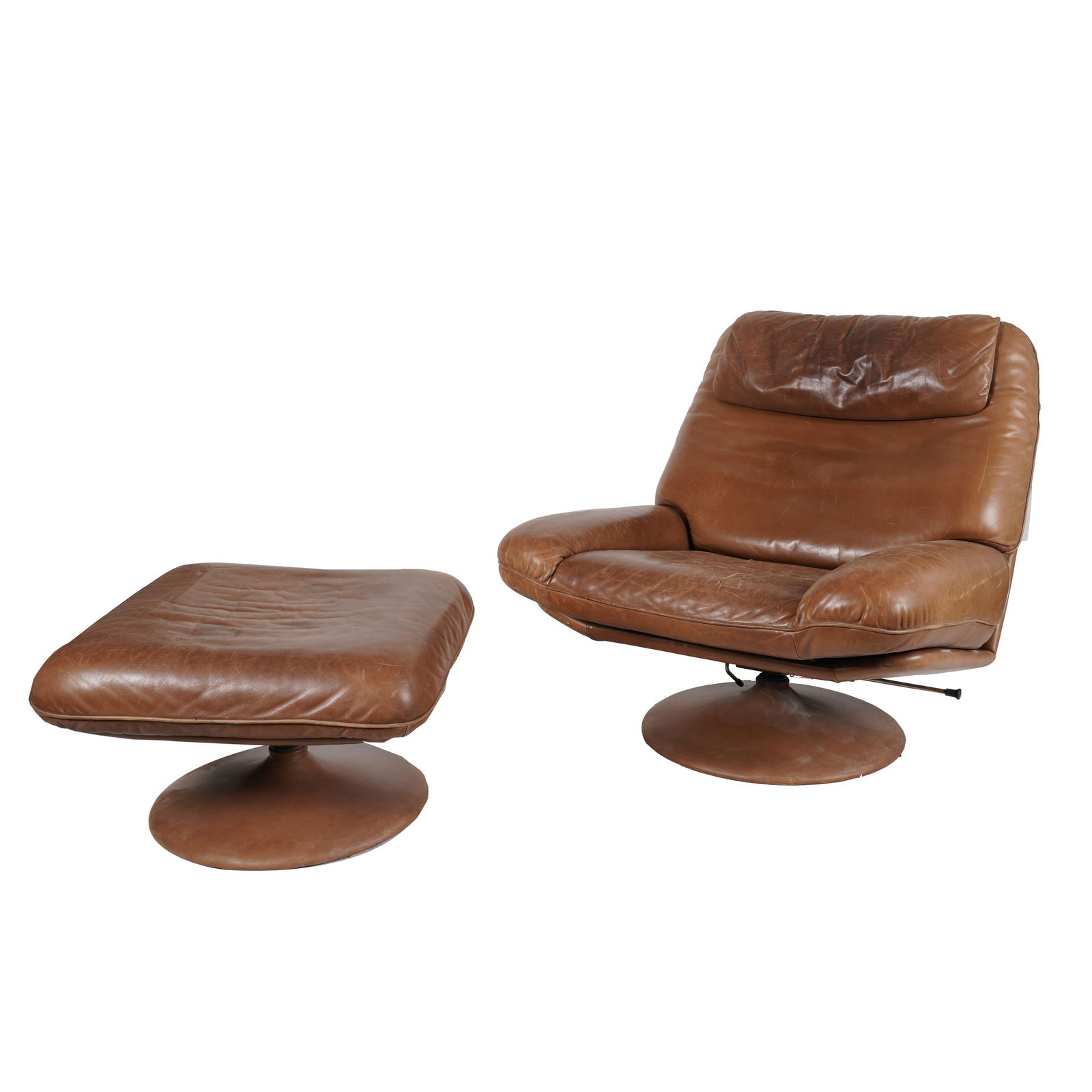 A De Sede DS 54 Swivel Lounge Chair and Ottoman: 1970s; upholstered with brown leather Chair: 37 x 36 x 32 in. (94 x 91.4 x 81.3 cm.), Seat height: 17 1/2 in. (44.5 cm.)