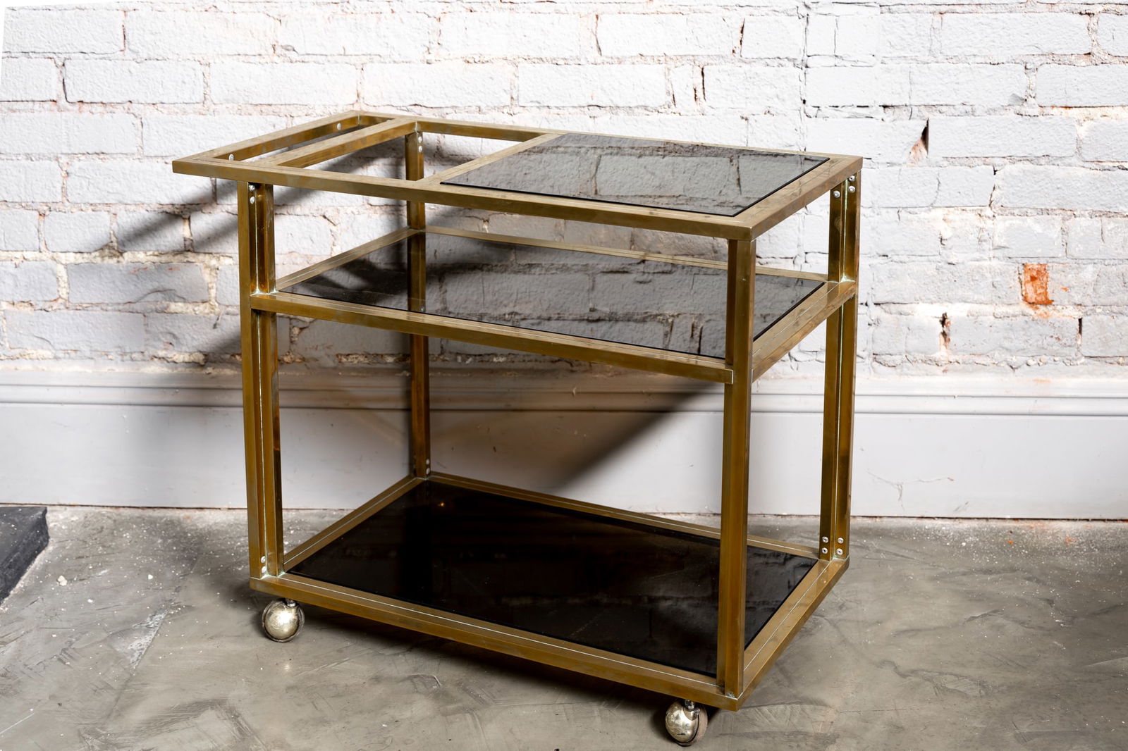 An Italian Brass and Smoked Glass Bar Cart: 1970s 24 x 29 x 16 in. (61 x 73.7 x 40.6 cm.) Provenance: The Private Collection of International Architect and Designer Selma Cisic and the iconic Los Angeles store Adesso.