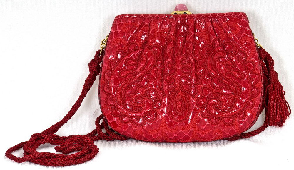 JUDITH LEIBER RED REPTILE AND EMBROIDERED HANDBAG: Red leather embroidered with red swirls; pink stone clasp; red rope strap 5 inches high; 7 inches wide