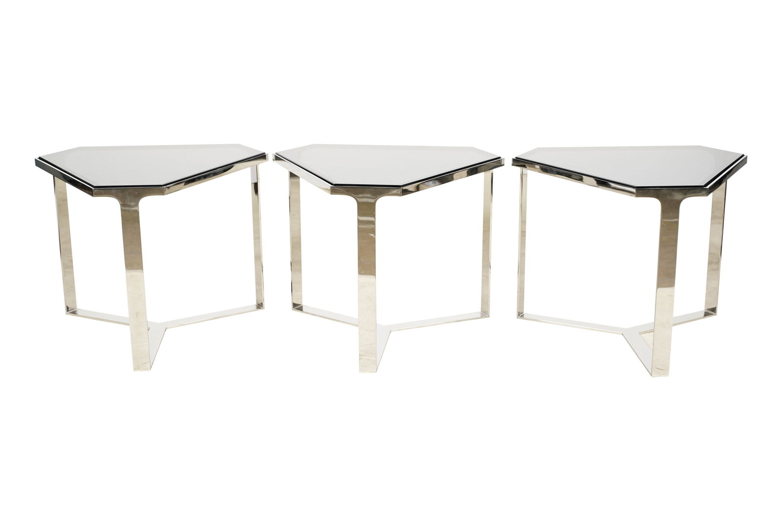 Three Angelo Donghia Triangular End Tables: "Forma" model; chromed metal, smoked glass Each: 17 1/4 x 22 1/2 x 19 3/4 in. (43.8 x 57.2 x 50.2 cm.) Notes: This item does not qualify for in-house shipping. Please see our preferred shippers list f
