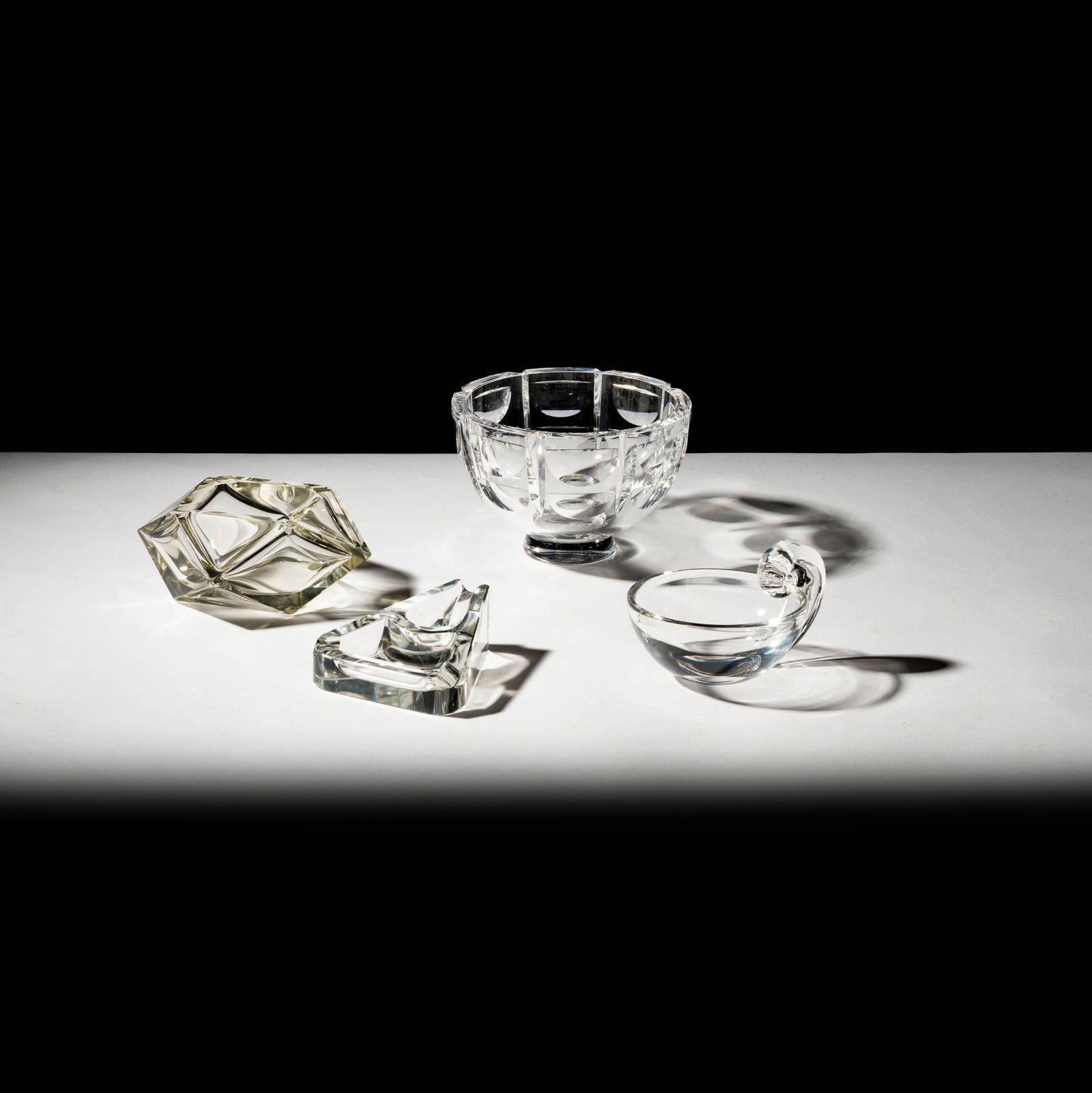 A Group of Crystal Tabletop Articles: comprising an Orrefors bowl, a Steuben candy dish, a large facet-cut ashtray, and a triangular cigar/pipe holder Bowl: 4 3/4 x 7 x 7 in. (12.1 x 17.8 x 17.8 cm.); [4 pieces]