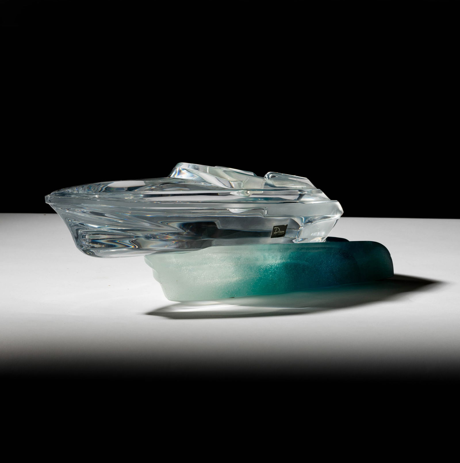 A Daum Pate de Verre Model of a Speedboat: "Monaco Powerboat"; clear glass and blue-green pate de verre, in two parts; etched "Daum France" to each part, the boat also with adhesive label "Daum France" Overall: 4 x 15 1/2 x 7 in. (10.2 x 39.4