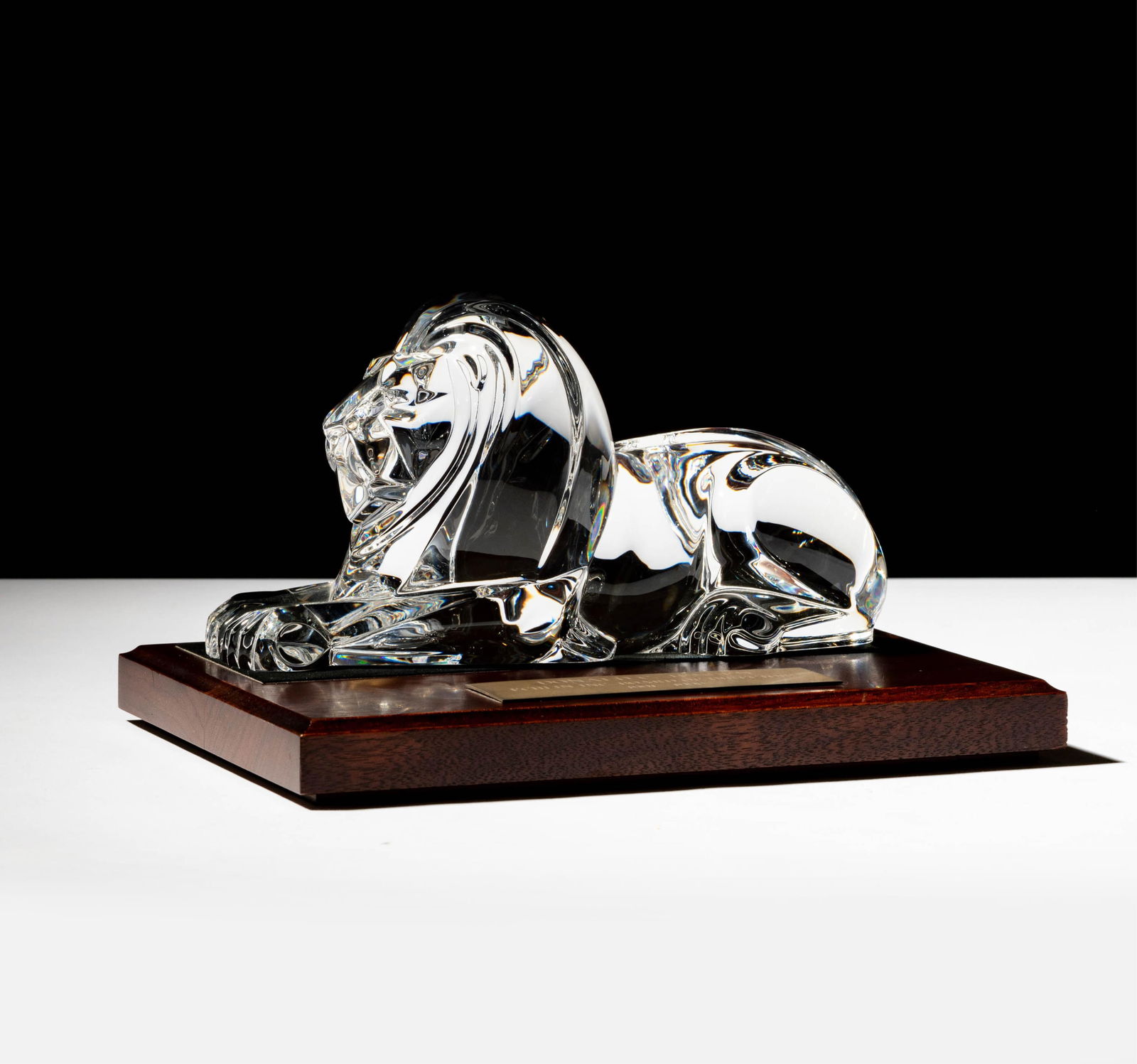 Steuben Glass Recumbent Lion Sculpture: on wooden base; signed "Steuben" and "Lloyd Atkins"; Overall: 5 x 9 x 6 1/4 in. (12.7 x 22.9 x 15.9 cm.); ; Provenance: The collection of Santa Barbara Steuben collector Joel Kreiner