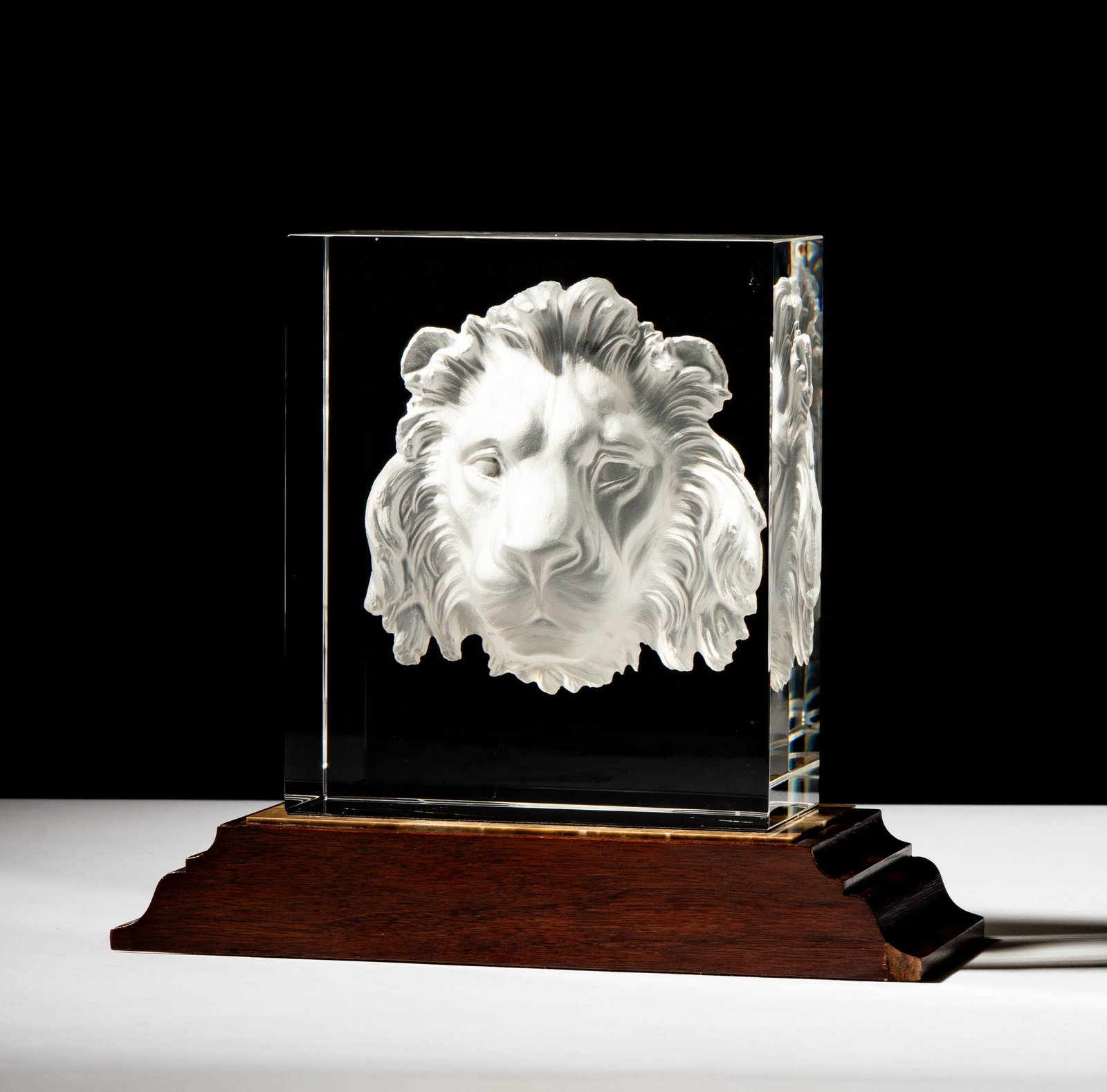 Steuben Glass Majestic Lion Sculpture: designed by Taf Schaefer,; on wooden base; signed; Overall: 8 x 9 1/4 x 4 in. (20.3 x 23.5 x 10.2 cm.); ; Provenance: The collection of Santa Barbara Steuben collector Joel Kreiner