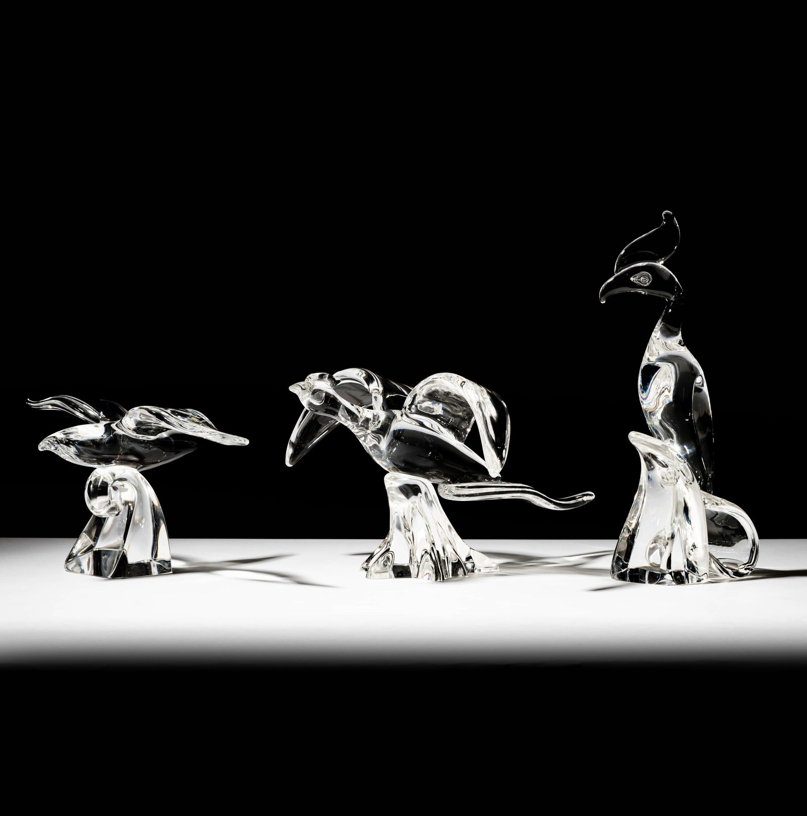 Three Steuben Glass Bird Sculptures: each signed; Ranging from 5 3/4 x 12 1/4 x 9 in. (14.6 x 31.1 x 22.9 cm.) to 13 in. (33 cm.) high; ; Provenance: The collection of Santa Barbara Steuben collector Joel KreinerNote: This item does not