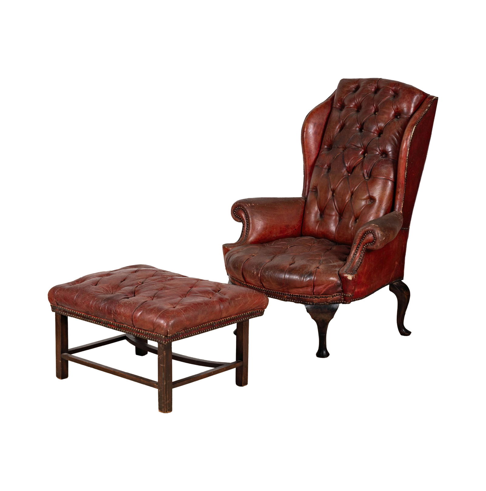 An English Leather Wing Chair: with an associated ottoman Chair: 49 x 37 x 31 in. (124.5 x 94 x 78.7 cm.) Seat height: 17 in. (43.2 cm.) back of leg with loss, leather with some tears and staining; Notes: This item does not qualify