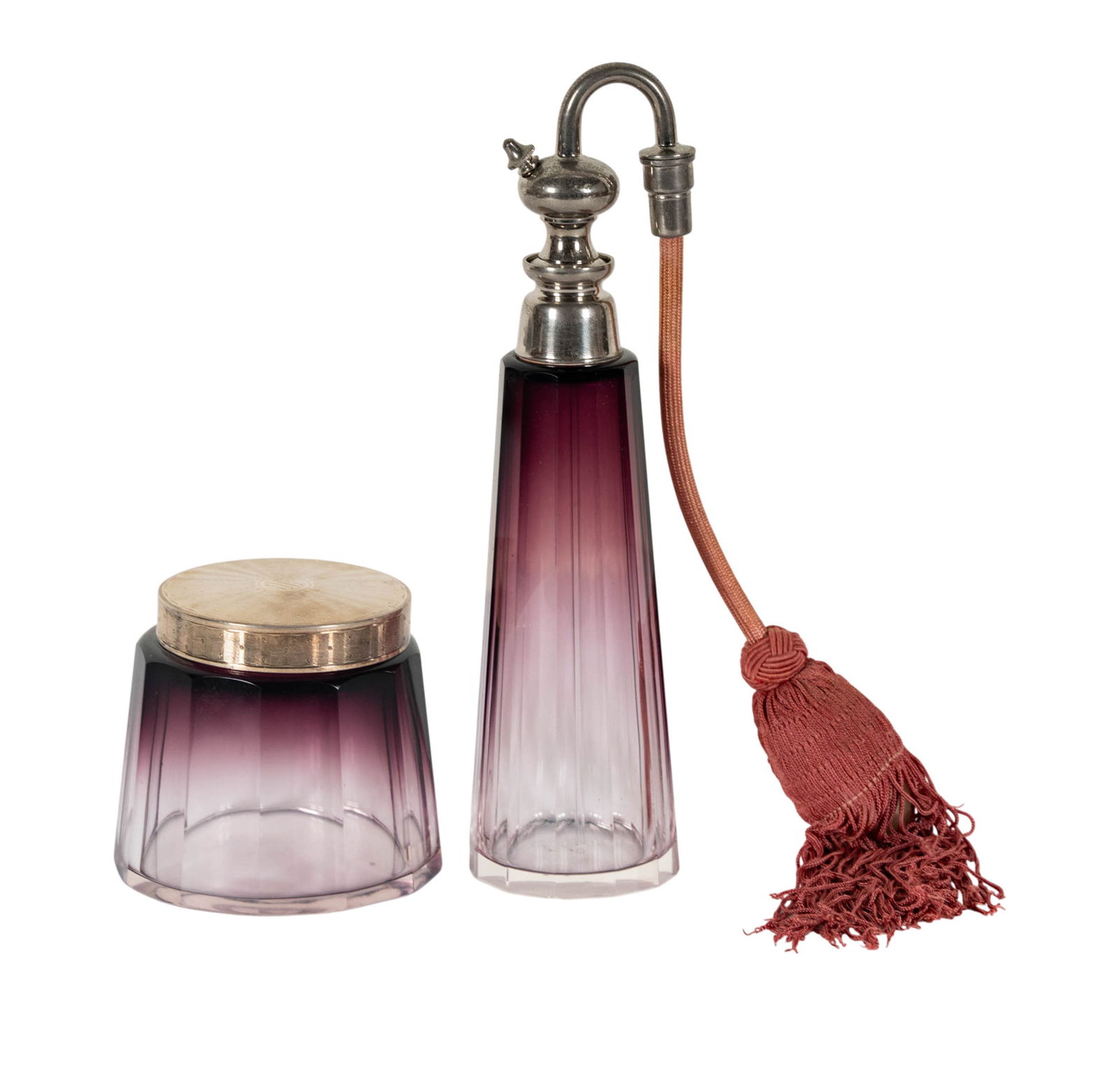 An Hermes Glass Vanity Set: comprising a clear-to-amethyst cut glass powder jar with metal lid marked "Hermes Paris", and a matching atomizer with bulb, unmarked 9 in. (22.9 cm.) high