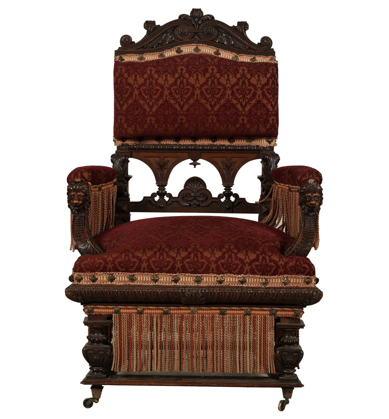 An English Renaissance Revival Carved Walnut Hall Chair: the arms with lion's head terminals; raised on casters 49 1/2 x 32 x 26 1/2 in. (125.7 x 81.3 x 67.3 cm.) Seat height: 23 in. (58.4 cm.)