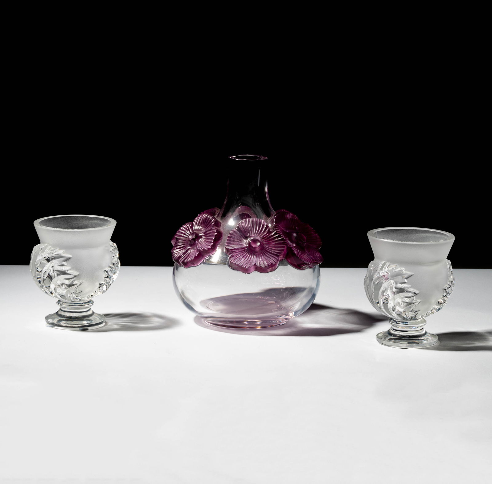 A Group of Three Lalique Glass Vases: comprising a pair in frosted and clear glass (Each 5 in. high), and one in clear and purple frosted glass (7 1/2 in. high); each signed "Lalique France" [3 pieces]