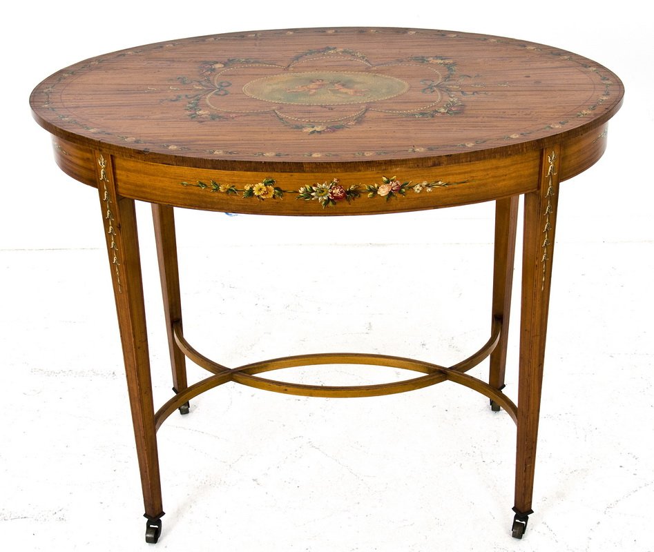 EDWARDIAN ADAMS STYLE PAINTED SATINWOOD TABLE: the oval top with a central painted medallion of cherubs and floral swag above tapered square legs and an entwined stretcher Provenance: Estate of David Copley, La Jolla 36 inches long; 23 1/2 inches 