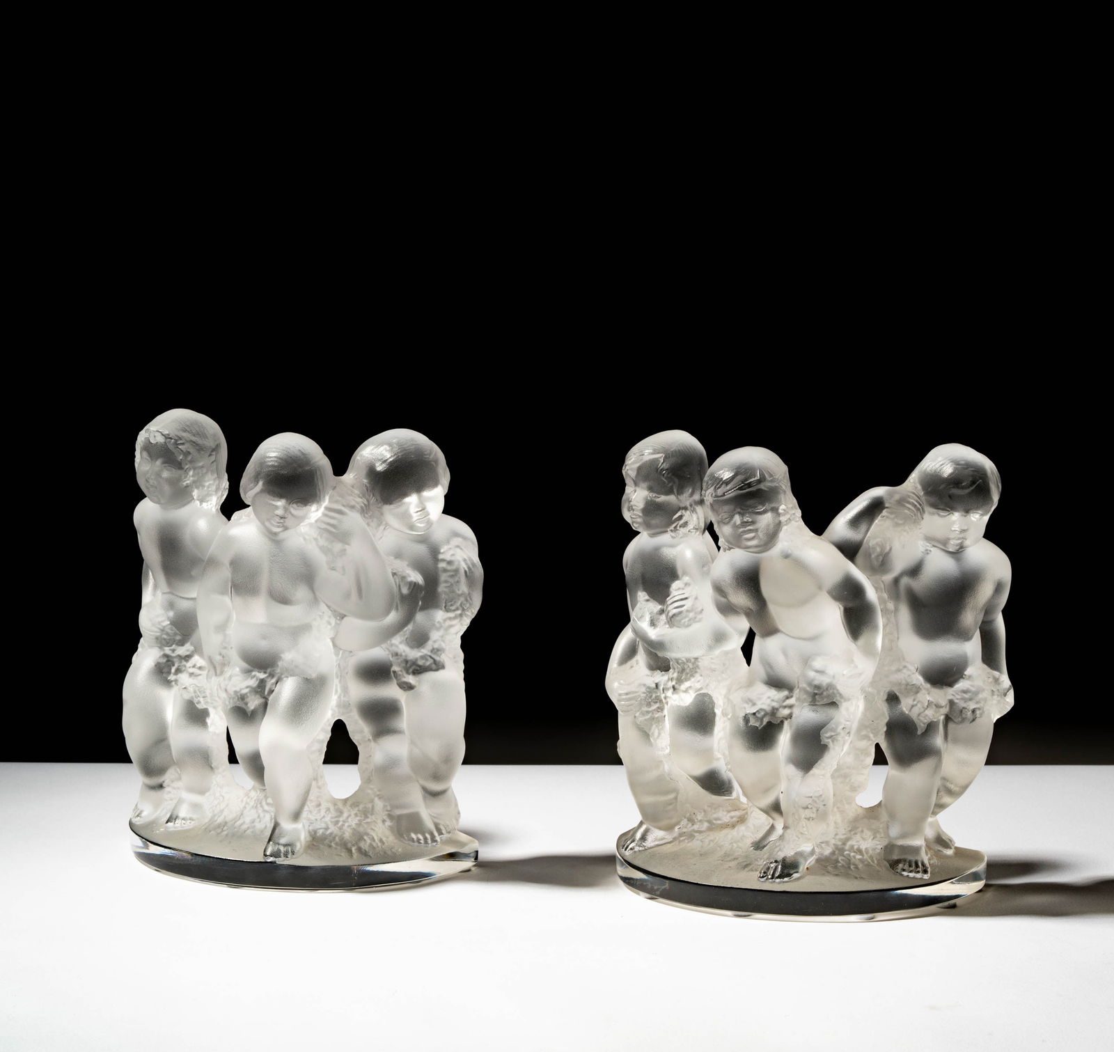 A Pair of Lalique Molded Glass Luxembourg Cherub Bookends: 7 3/4 x 6 1/2 x 3 1/4 in. (19.7 x 16.5 x 8.3 cm.),