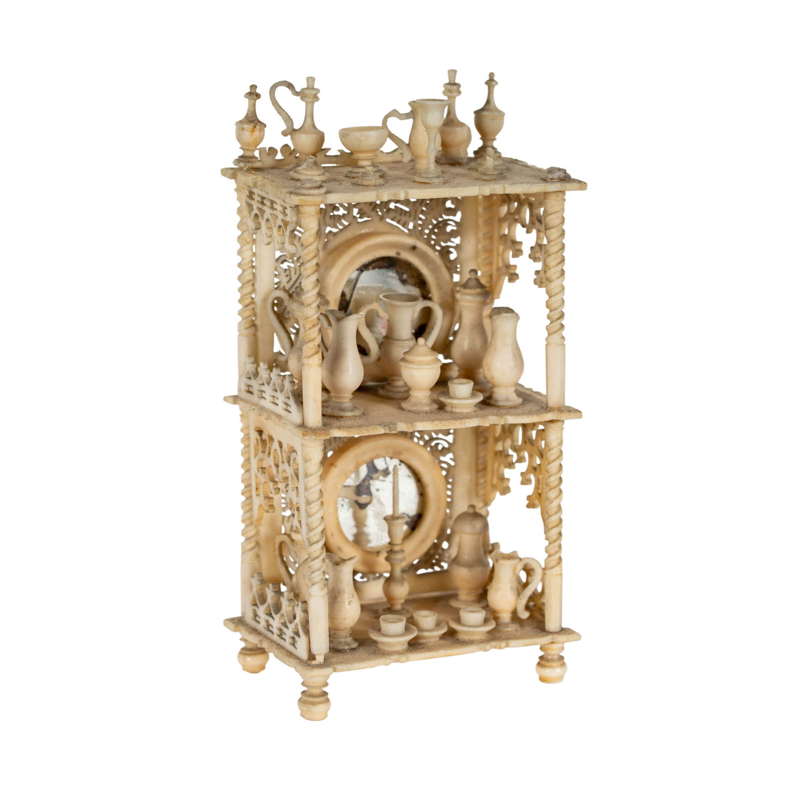 A Napoleon III Carved Bone Miniature Etagere: France, c. 1870, arrayed with cups, vases and pitchers on three shelves joined by barley twist supports and with two rear panels each ornately pierced and inset with a mirror-glass roundel, the sides