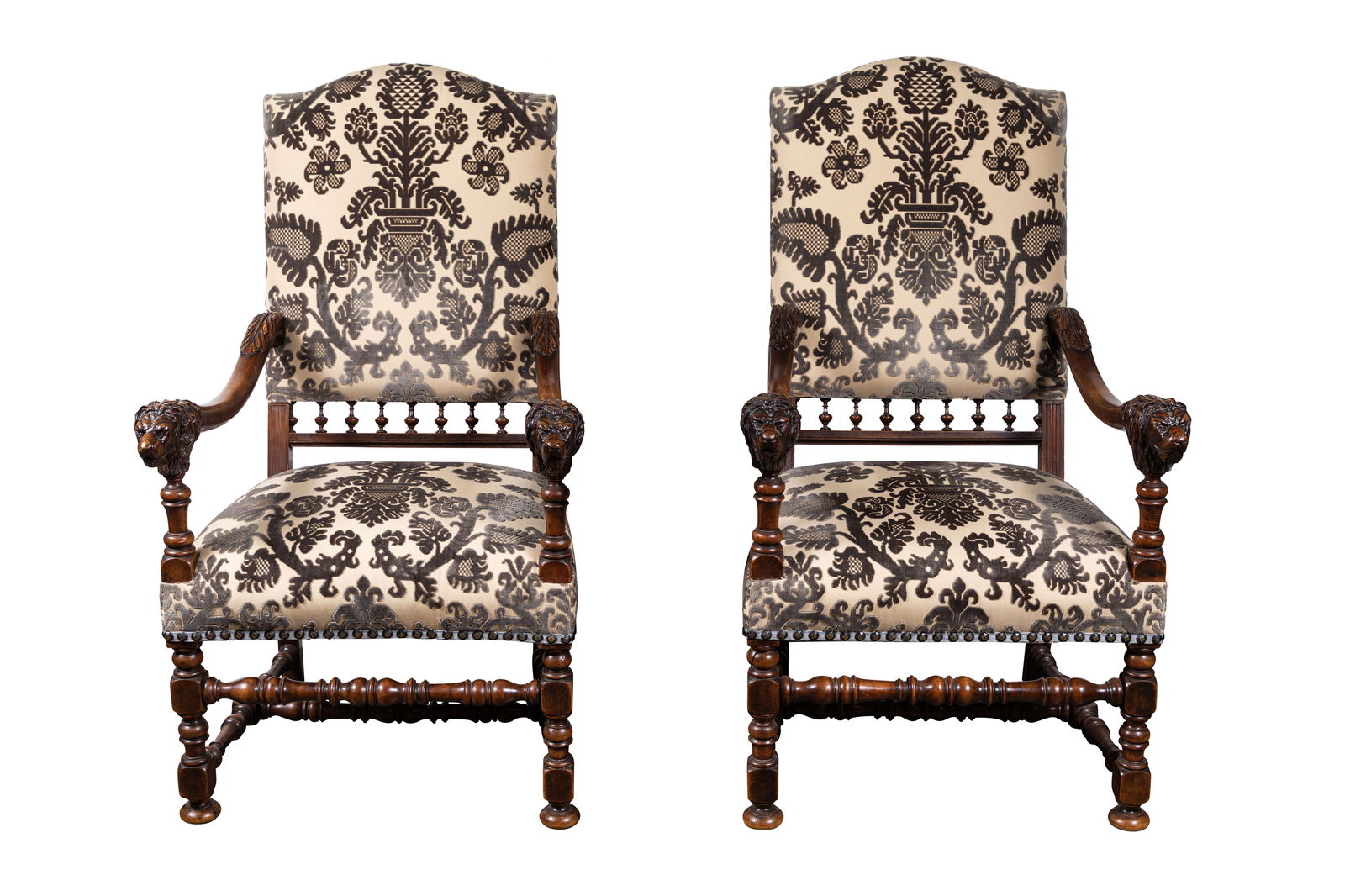 A Pair of Italian Carved Walnut Armchairs: late 19th century, with lion's head armrest terminals, turned legs and stretchers, and newly upholstered in silk velvet, each: 45 1/2 x 26 1/4 x 31 1/4 in., seat height: 20 1/2 in.