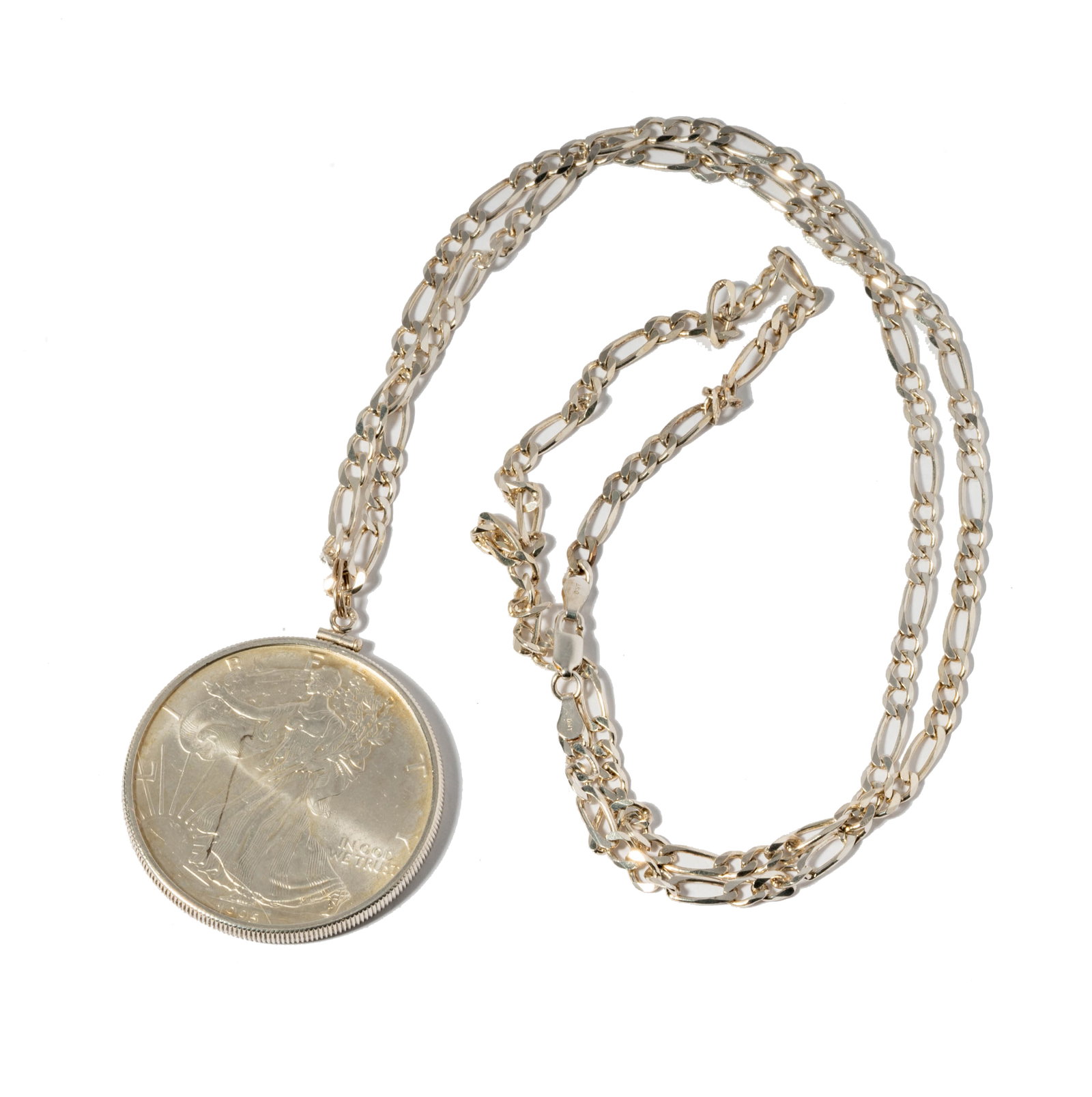 Sterling Silver Figaro Chain and Silver Dollar Liberty Coin Pendant: Sterling Silver Figaro Chain and Silver Dollar Liberty Coin Pendant including one framed United States silver dollar pendant measuring 47.42mm tall, including bale and figaro chain measuring 29-1/2