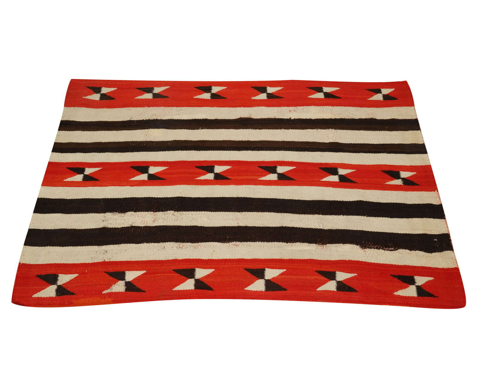 A Navajo Chief Design Blanket: late 19th century, with wide black and white stripes separating three red bands, each containing six black-and-white triangular elements forming hourglass shapes. Wider-than-long weave, as opposed to 