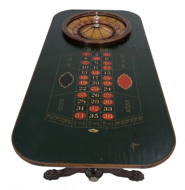 AMERICAN ROULETTE TABLE: the walnut burlwood wheel with a silver-plated knob inscribed "The Geo. Mason Co. Makers, Denver Colo.," set into a rosewood trestle table, the surface fitted with a hunter green, hand painted oil clo