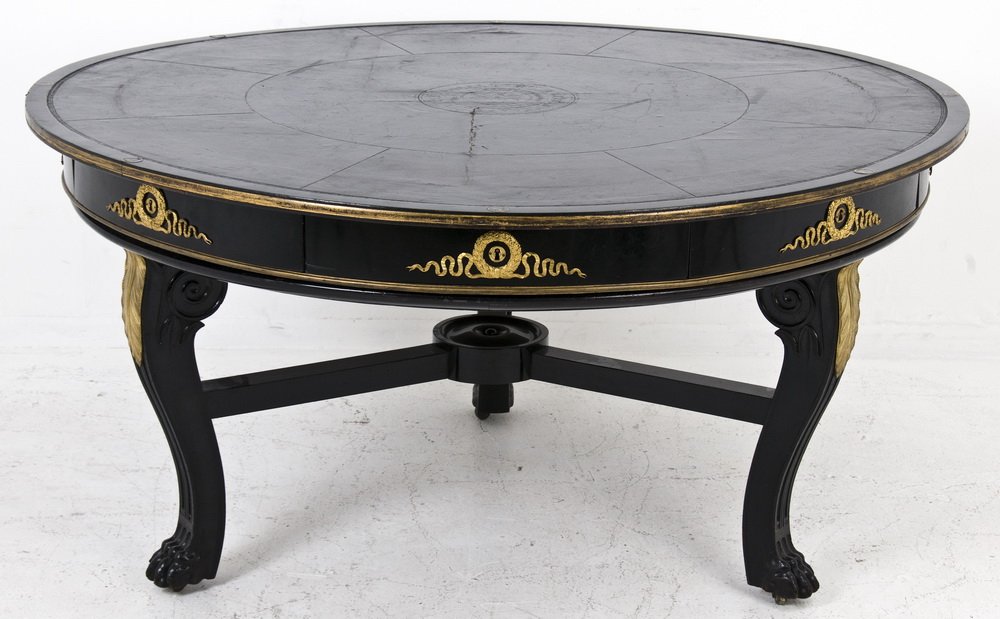 ITALIAN EBONIZED GAMES TABLE: the round leather lined top having brass numerals around the perimeter, over eight ebonized frieze drawers each with a gilt bronze wreath and ribbon escutcheon, on three cabriole and claw foot support