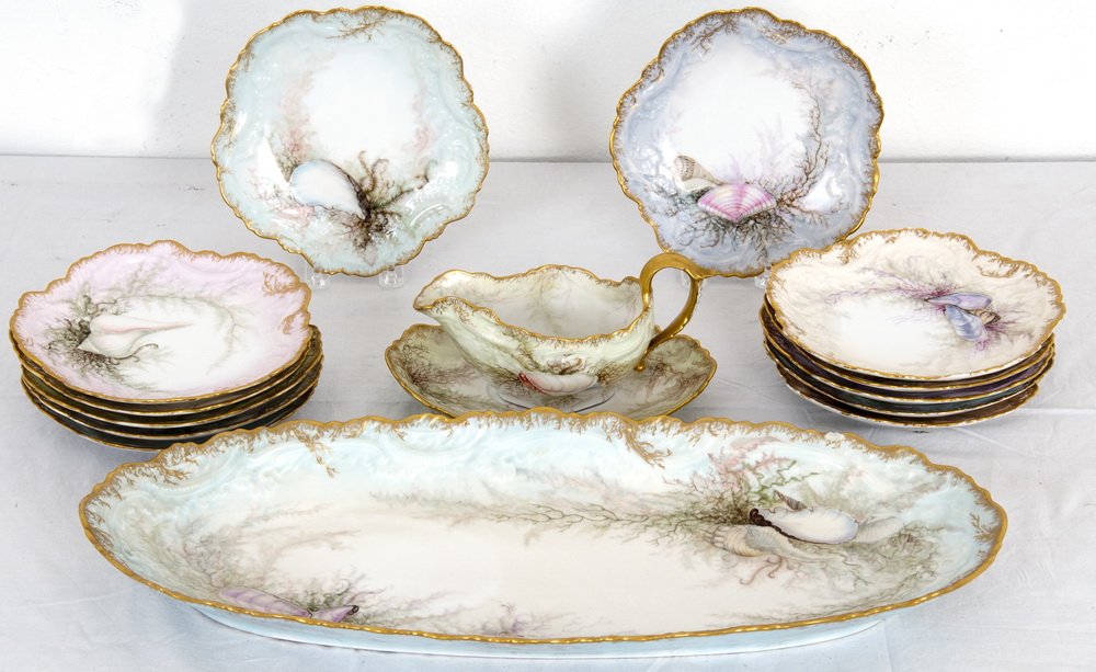 HAND-PAINTED LIMOGES FISH SERVICE: circa late 19th century comprising of an oblong platter, a sauce boat and under plate, and twelve plates, each hand-painted painted with seashells and having gold painted rims; marked V.F Limoges Fran