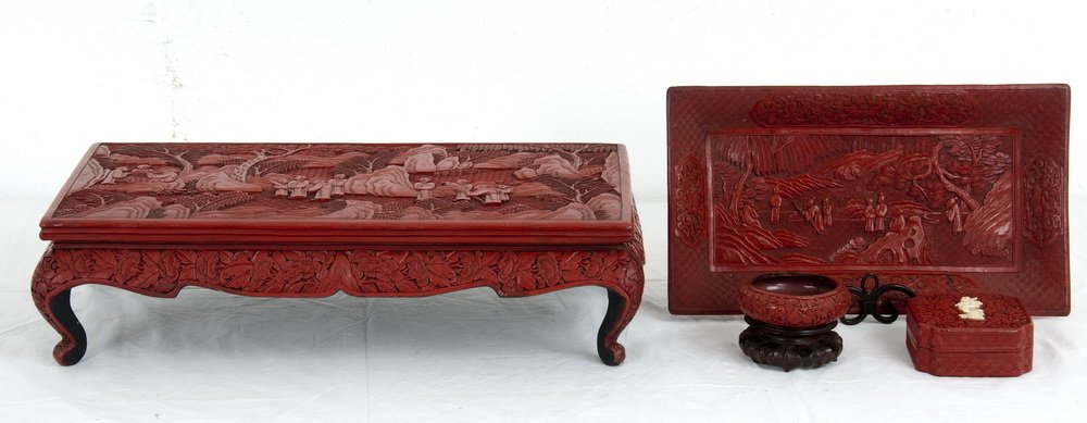 FOUR CHINESE CINNABAR LACQUERED TABLE ACCESSORIES: Qing Dynasty; the low stand and tray carved with figures in a landscape, together with a bowl on stand and a square box with a central carved figure the stand measuring 20 1/2 inches wide; 11 inches d