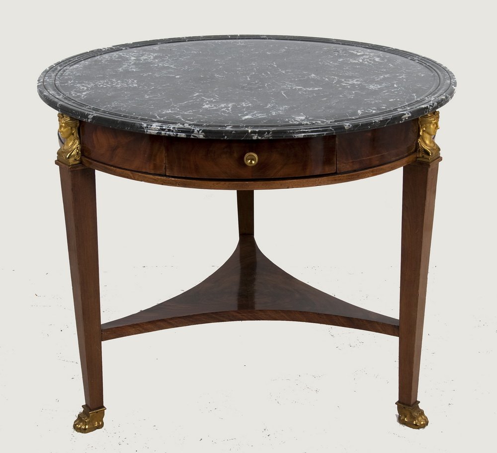FRENCH EMPIRE STYLE MAHOGANY MARBLE TOP TABLE: the round black marble top above a single frieze drawer, gilt bronze female masques at the knees, a tripartite lower tier and three tapering square supports with gilt bronze paw feet 38 1/2 inches dia