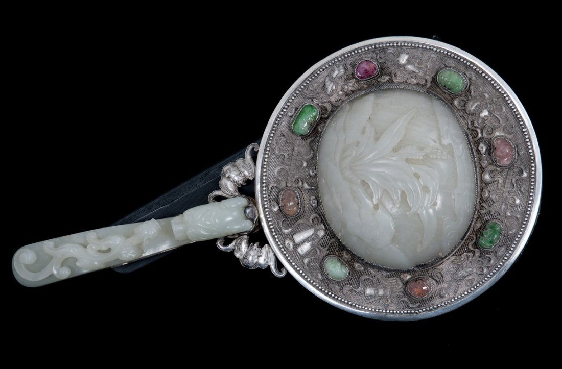 CHINESE CARVED JADE & SILVER HAND MIRROR: the carved plaque with a foliate relief surrounded by a filigree silver case with carved precious stone inlay and silver bat-form handles supporting a carved jade buckle 9 1/2 inches long