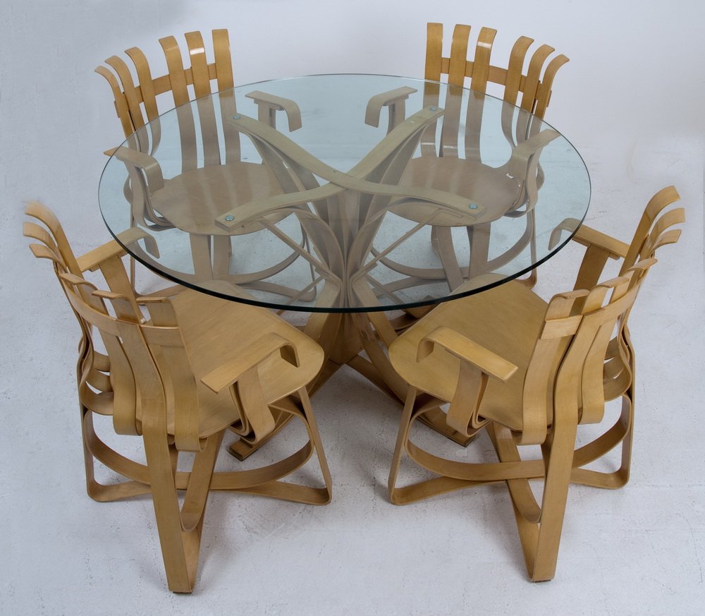 FRANK GEHRY FOR KNOLL BENT MAPLE TABLE & FOUR CHAIRS: circa 1996-1997 "Face Off" table and "Hat Trick" chairs the table having a round glass top each stamped below with the Knoll logo, Gehry signature, and date of production the table measuring 47 1/2 in