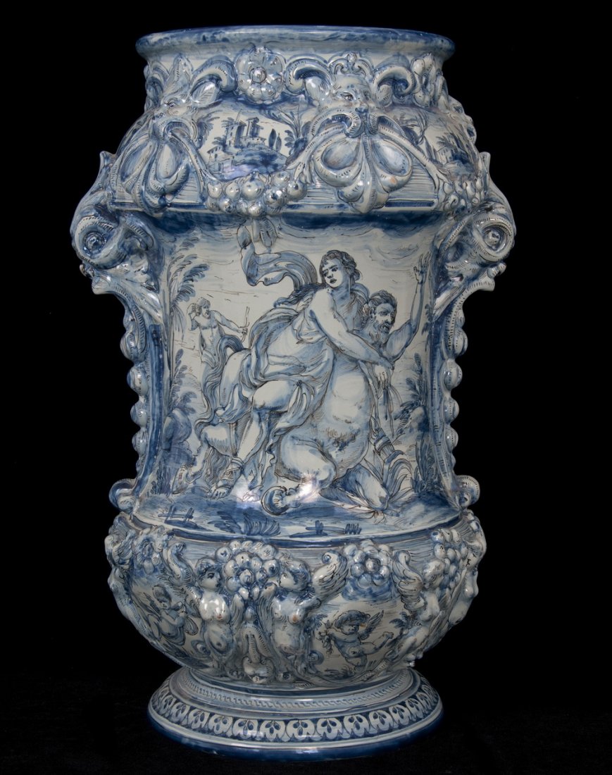 FAIENCE BLUE & WHITE GLAZED POTTERY VASE: a pair of acanthus form handles flanking floral and lion masque relief designs and classical scene reserves with satyrs and cherubim Provenance: with U.S. Customs label below from the Panama-Pacific I