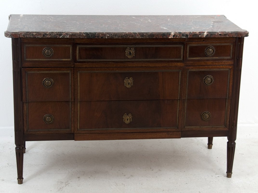 LOUIS XVI STYLE MARBLE TOP COMMODE: the rouge marble top above a case of six short drawers flanking three long, central drawers and having gilt bronze trim, escutcheons, and ring pulls, on tapering fluted legs 51 1/2 inches wide; 20 3/4