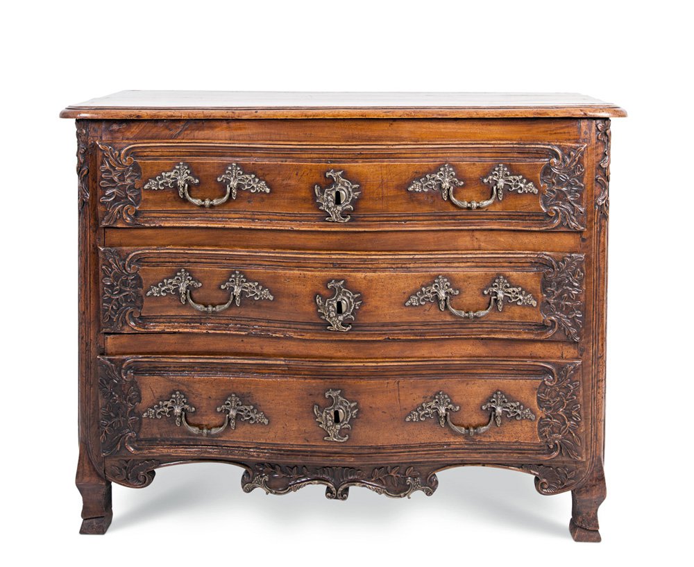 FRENCH PROVINCIAL SERPENTINE CHEST: the serpentine plank top over a conforming case of three drawers, each with foliate designs carved on either short end and two bronze floral loop handles flanking a rocaille escutcheon, over a scrolli