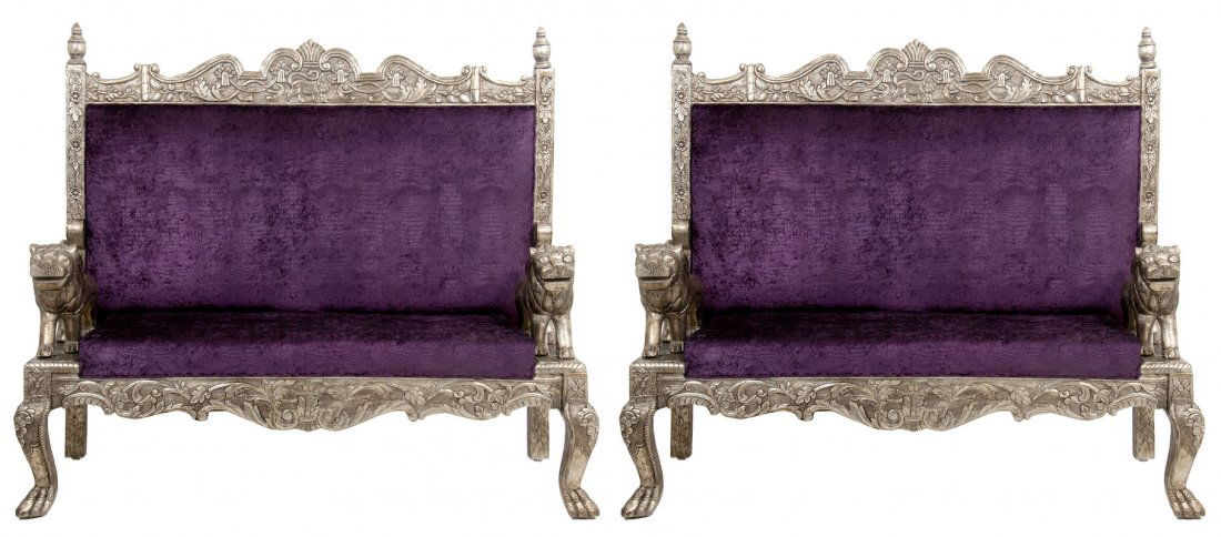 A PAIR OF INDIAN REPOUSSE SILVER VENEERED SETTEES: the carved backs surmounted with a frieze centered by a lion and floral motif, flanked by two carved lions mounted as arms atop classical carved legs 59 inches wide;
