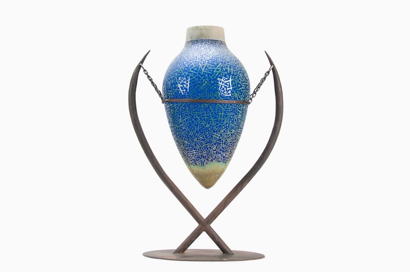 DUNCAN MCCLELLAN: ETCHED GLASS AMPHORA: the blown, layered and etched glass amphora in royal blue to green with metallic collar suspended on a double arm metal stand 20 inches high; 12 inches diameter