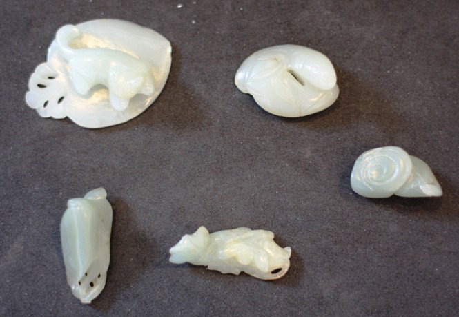 A collection of five celadon jade pendants: comprising a cat lying on a large leaf, two fish curled up together, a magnolia blossom, a fish and lotus flowers, and a lingzhi spray. The first, H. 64mm Provenance: From the Leo Walker Tattersfield 