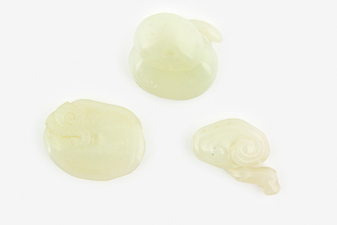 Three pale celadon jade lingzhi carvings: two carved with the stem curled behind the mushroom head, the third carved as open, all with loop holes The largest, W. 40mm Provenance: From the Leo Walker Tattersfield Collection of Chinese Jades