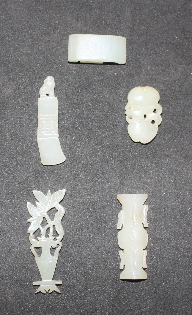 A group of five miniature pale celadon carvings: comprising an archaistic blade and Buddhist lion, a vase and blossoms, a peach group, a sword slide and an archaistic handled vase fitting The largest, H. 45mm Provenance: From the Leo Walker Tattersf