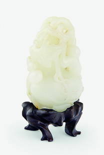 A pale celadon jade carving: of a monkey climbing an oversized double-gourd amongst leaves and further smaller gourds, wood stand H. 55mm