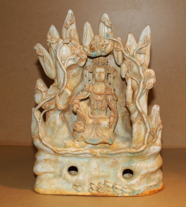 A Chinese Qingbai-style Buddhist Guanyin shrine: modeled as a rockwork grotto centered by a figure of Guanyin seated at ease on a ledge, the opening framed by scrolling flowering branches H. 305mm