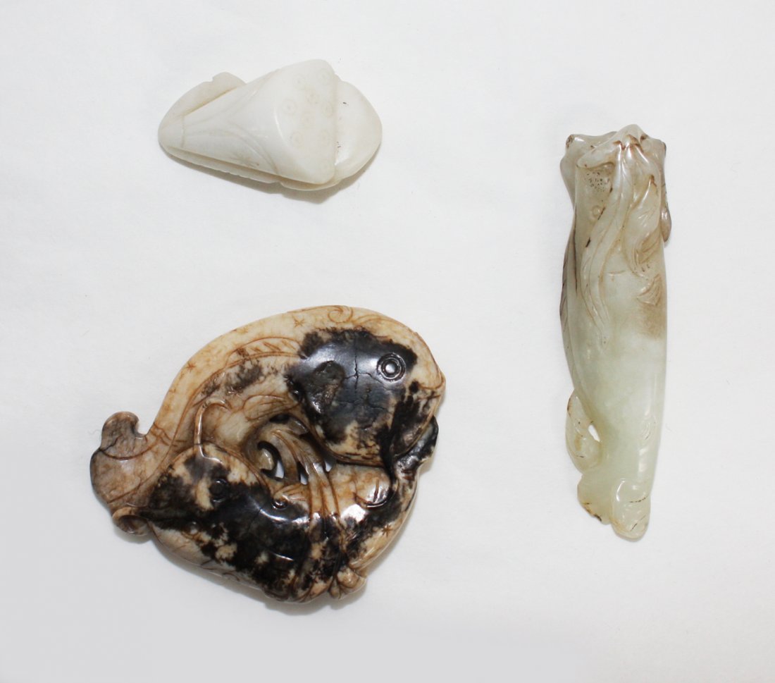 Chinese celadon jade pendant: carved as a fish swimming amongst seaweed, and an opaque cream and black jade carp group and an opaque white jade fish and lotus group. The first, L. 75mm Provenance: From the Leo Walker Tattersfield 
