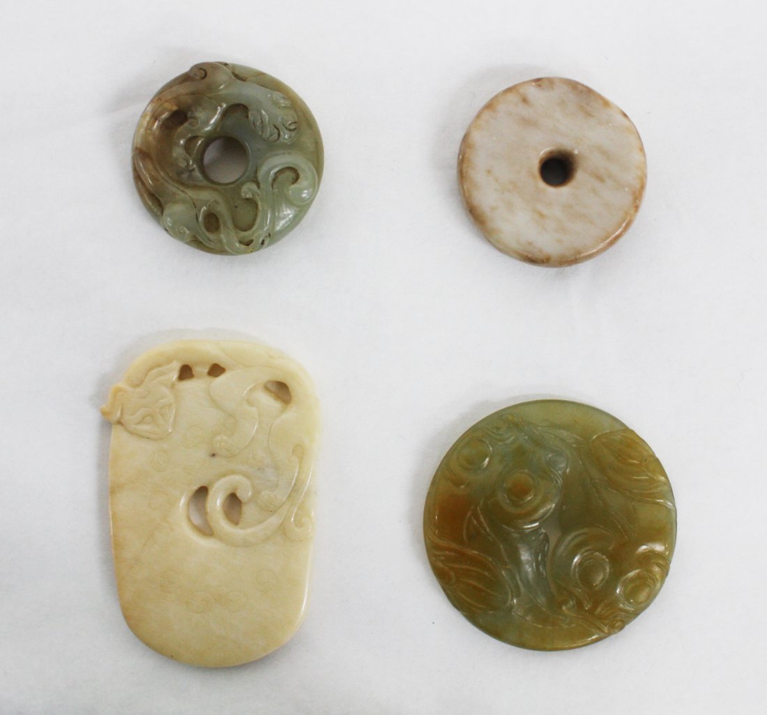 Chinese celadon and grey jade bi disc: carved with a chilong dragon to the top, a celadon jade circular pendant carved with two fish and two cream opaque jade bi discs. The first, D. 38mm Provenance: From the Leo Walker Tattersfield Collec