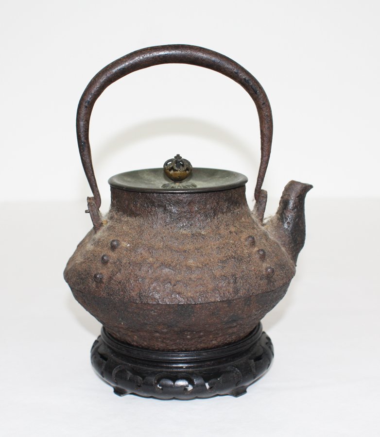 Japanese iron kettle: with metal handle and cover, wooden stand. W. 180mm Provenance: Previously in the Len Castle Collection. Pat Booth Collection.