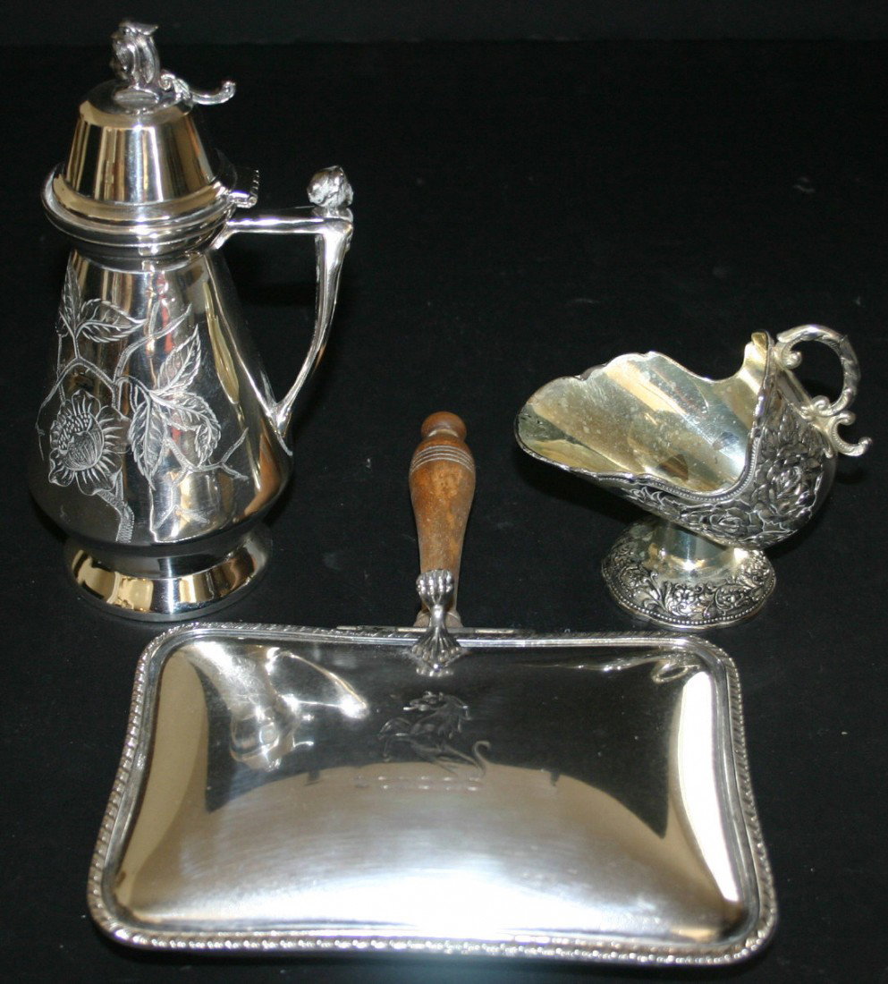 Three (3) pieces. Silverplate handled syrup face : Three (3) pieces. Silverplate handled syrup face finial Pairpoint, Elaborate sugar skuttle. Wooden handle lidded crumb butter. 8 1/4" tallest.