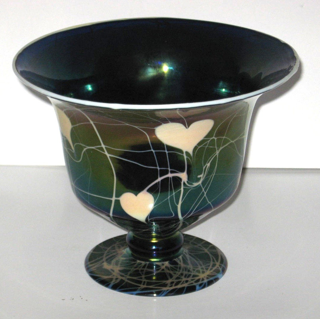 Imperial Free Hand iridescent compote,: pedestal bowl form in dark blue glass decorated with white hearts and vines with a mirror iridescent finish, 8 1/4" wide.