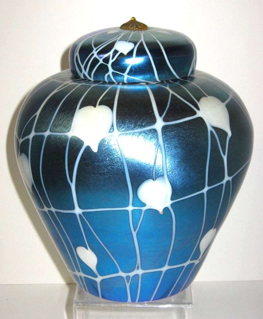 Durand covered ginger jar,: ovoid form in iridescent blue decorated with white heart and vines and adorned with an amber raspberry prunt finial, 9 1/2" ht. LITERATURE: see Durand the Man and His Glass" page 69 for exact example.