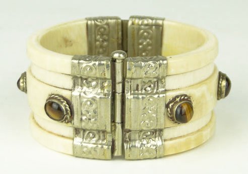SILVER AND IVORY BANGLE BRACELET: SILVER AND IVORY BANGLE BRACELET Ornately Carved Bangle Bracelet with Silver Hinge and Cabochon Tigers Eye Stones Measures Approximately 3 Inches Wide WE WILL SHIP THIS ITEM FOR $20 PLUS INSURANCE, NO