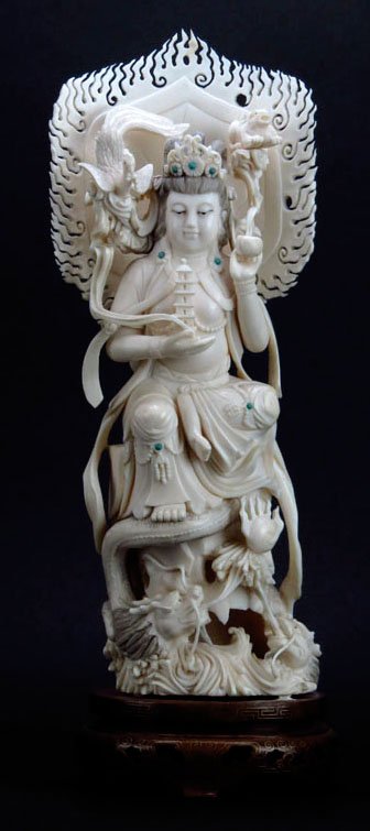 IMPORTANT ANTIQUE CHINESE CARVED IVORY GODDESS: Measures an impressive 13.5" tall sits on 2" wooden base. Fabulous carving with turquoise inset accent. She sits upon 2 dragons holding a foo lion and bird of paradise with carved fan behind her. The 