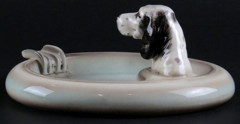 Vintage Goldscheider Porcelain Cigar Ashtray with Dog: Vintage Goldscheider Porcelain Cigar Ashtray with Dog Head. Signed. Small Chip to Lip of Holder or else Good Condition. Measures 3-1/2 Inches Tall and 8 Inches Long. Shipping $20.00