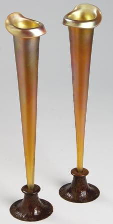 Pr. QUEZAL ROYCROFT Bud Vases: Pair of Quezal bud vases in unsigned Roycroft copper holders. Bases are original patina all over hammered with rivets around edges. Vases are elegant, slender tapering form with top edge turned up and