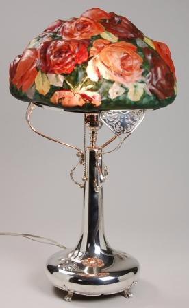 PAIRPOINT ROSE PUFFY LAMP: PAIRPOINT Rose Puffy reverse painted shade has an all over design f pink and red roseg on green background. Supported by a Pairpoint Art Nouveau plated base. 10" ring. Base appears to have been re sil